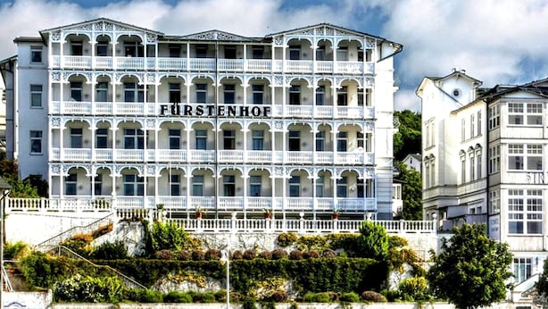 A multi-story building with the name "FÜRSTENHOF" prominently displayed. It features balconies, a stone facade, and a waterfront location. - Fürstenhof Rügen (Sassnitz)