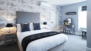 Een moderne slaapkamer met een groot bed, twee nachtkastjes met lampen, een bureau met stoel, en een kledingkast.