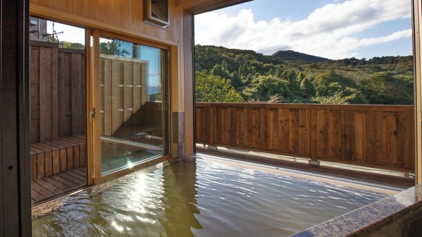 Ein Holzinnenraum mit einer Glastür, die zu einem Balkon mit Blick auf eine bewaldete Landschaft führt.