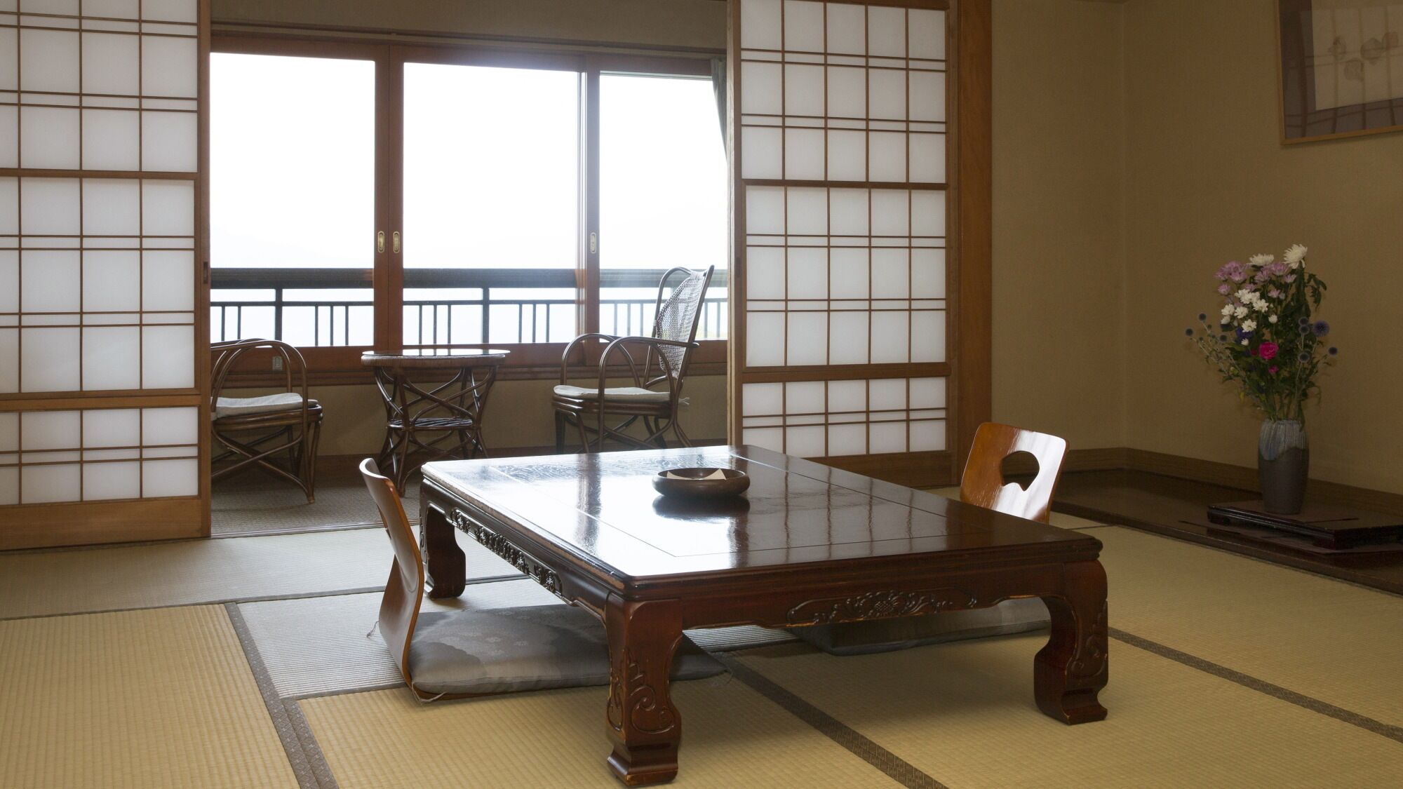 A traditional Japanese room with tatami flooring, a low wooden table, and sliding doors.