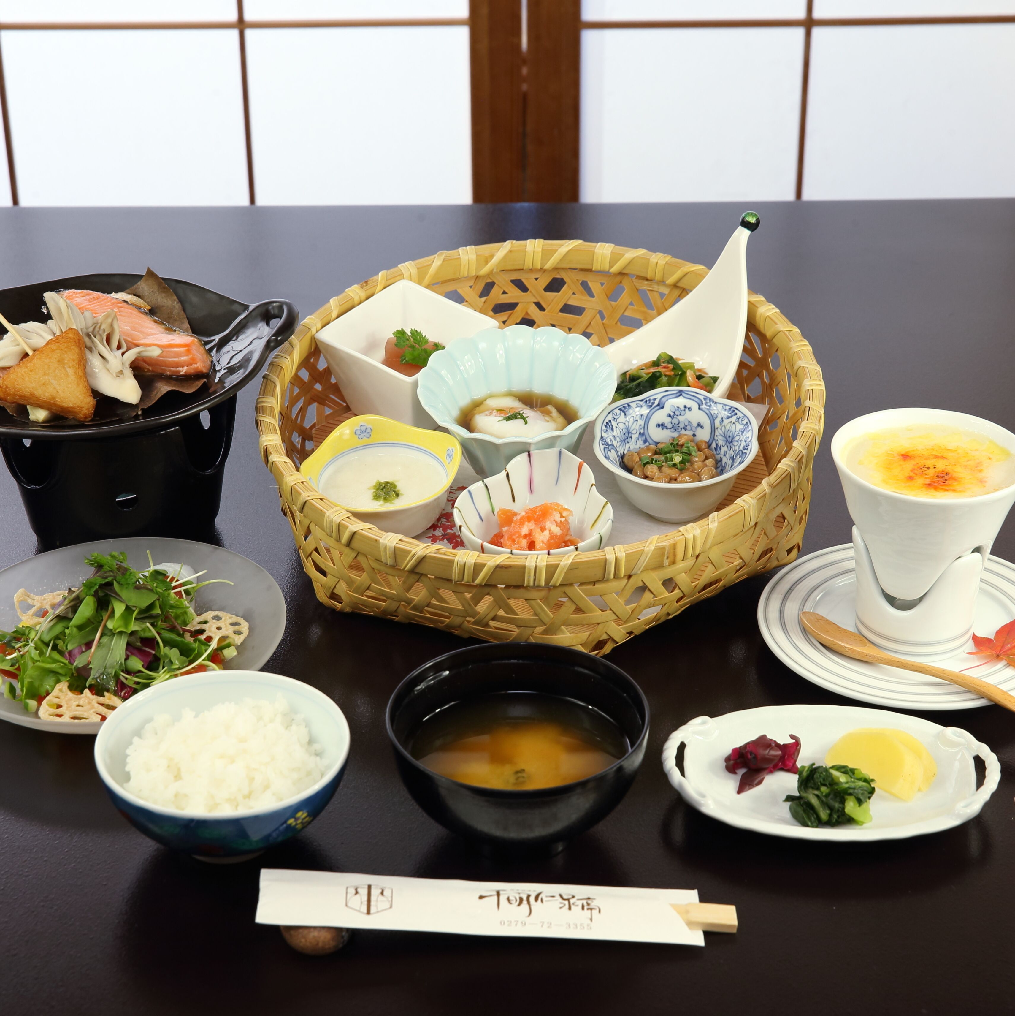 Una mesa servida con diversos platos, incluyendo una cesta de alimentos, tazones de sopa y platos de verduras.