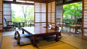 Ein traditioneller japanischer Raum mit Tatami-Böden, einem niedrigen Tisch und verschiebbaren Türen.