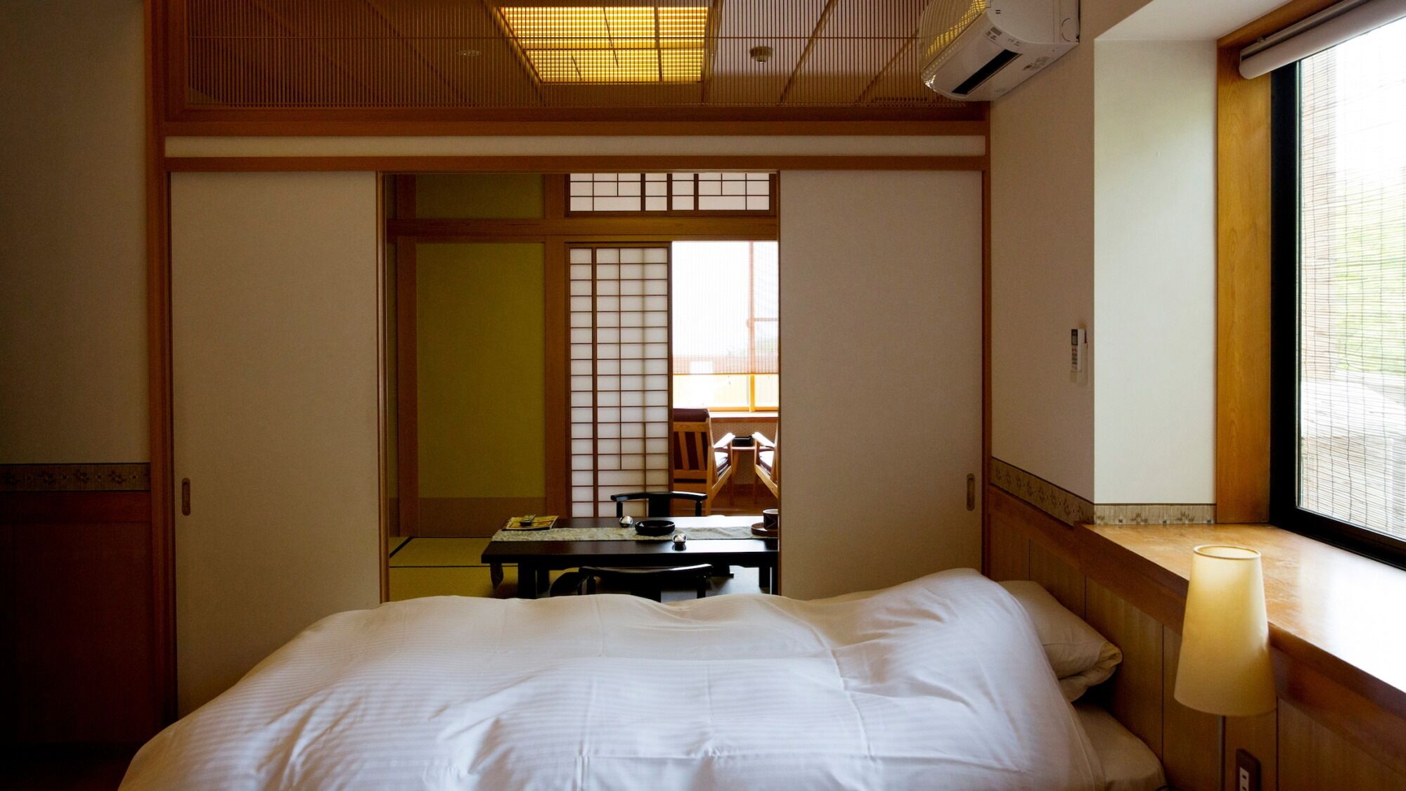 A hotel room with a bed, a desk, and a window.