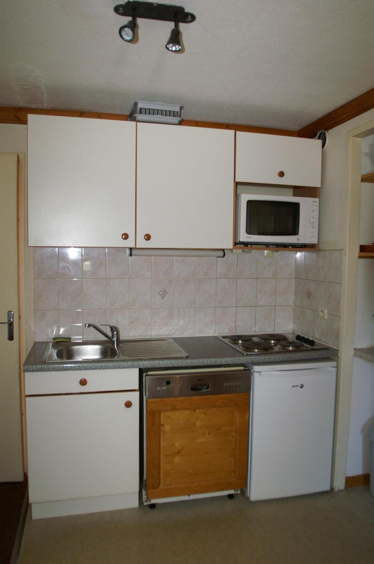 A compact kitchen with white cabinets, a microwave, a sink, a dishwasher, and a stove.