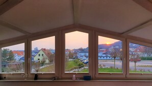 Una habitación con un amplio ventanal que da a una zona residencial al atardecer.