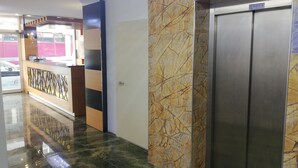 Eine Hotelhalle mit einer Rezeption, einer Marmorwand und einem Aufzug.