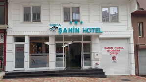 Ein Gebäude mit einem Schild, auf dem „Bursa Sahin Hotel“ steht, und einer geschlossenen Garagentür mit dem Schild „Sahin Hotel Otopark Girişi“.