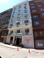 Um edifício de vários andares com uma placa indicando 'SAHIN HOTEL' no andar térreo.