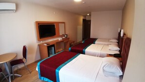Ein Hotelzimmer mit zwei Einzelbetten, einem Schreibtisch mit Stuhl, einem Fernseher und einer Minibar.