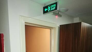 Un couloir avec une armoire en bois, un escalier et un panneau indiquant la sortie.