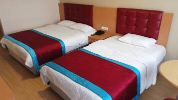 A hotel room with two beds, each with a red and blue bedspread, a wooden headboard, and a bedside table with a phone.