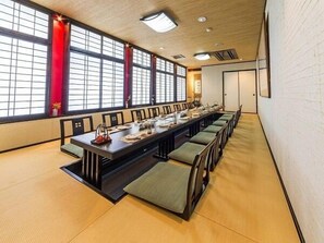 Un salón de conferencias con una larga mesa, sillas y ventanas amplias.