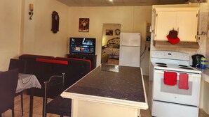 A compact kitchen with a dining area, a refrigerator, a stove, and a television. - Stewart Hotel Apt - Trincity, Airport, Full Apt (Trincity)
