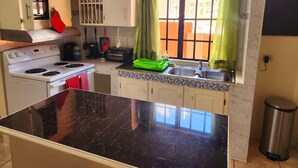 Uma cozinha compacta com fogão, pia e uma janela com cortinas.