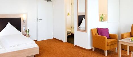 Habitación de hotel con cama, una silla, una mesita con frutas y televisión.