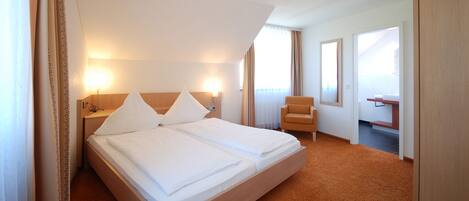 A hotel room with a large bed, two bedside tables, a chair, and a desk.