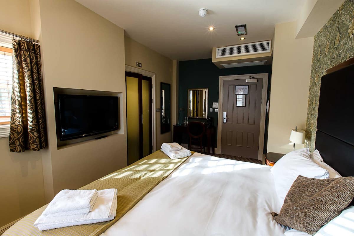 A hotel room with a bed, a television, a desk, and a door.