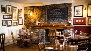 A restaurant interior with stone walls, framed pictures, a menu board, and tables set for dining. - The Maltsters Arms (Cardiff)