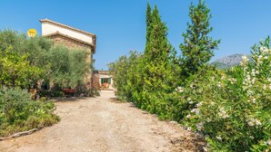 A rural path leading to a traditional stone building with a tiled roof, surrounded by lush greenery and flowering plants. - VILLA FRONTERA - Villa with private pool and views to the mountains in Soller Free WiFi (S��ller)
