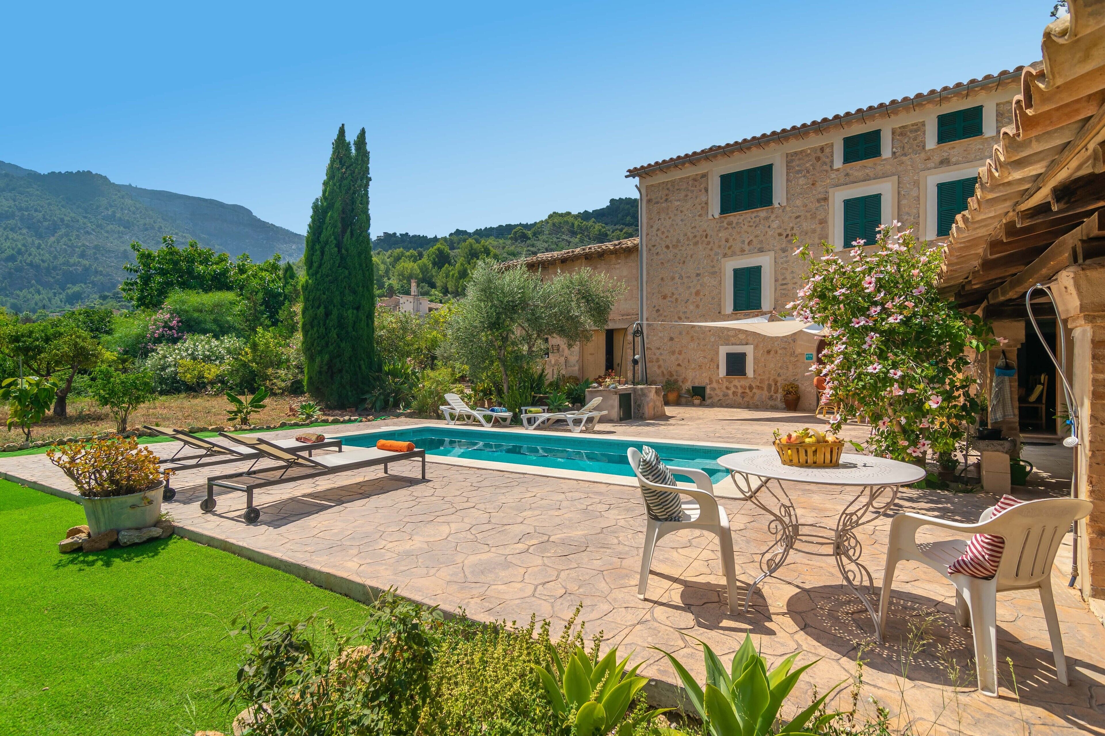 A stone building with a swimming pool, outdoor seating, and a well-maintained garden.