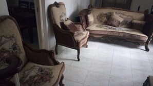 Une pièce comprenant deux fauteuils en bois richement décorés et un canapé, tous recouverts d’un tissu à motifs floraux.