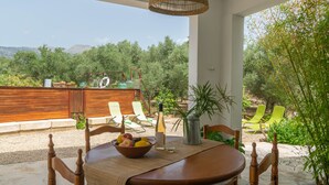 Zona d'esmorzar a l'aire lliure amb una taula, cadires i un bol de fruita.