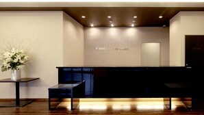 Un área de recepción con suelo de madera, un mostrador de recepción y un letrero en la pared.