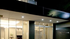 Una entrada de hotel moderna con puertas de vidrio, mostrador de recepción y un espacio interior visible.