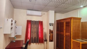 A room with a desk, chair, wardrobe, and a window with red curtains. - Stewart Suite Apt -Trincity, Airport, Full Apt (Trincity)
