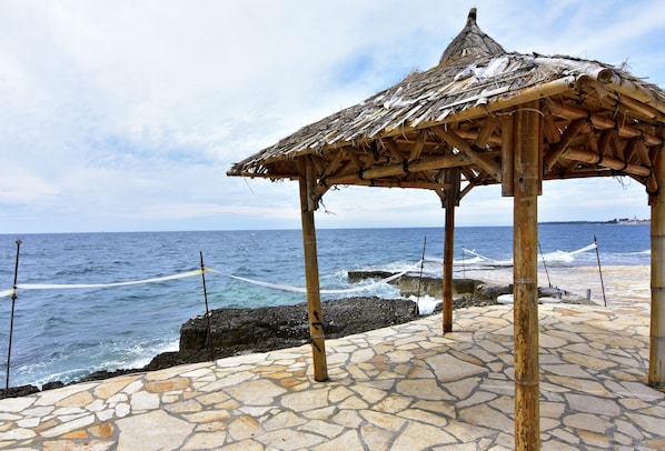 Une zone de plage dallée de pierres, avec une structure en bambou.