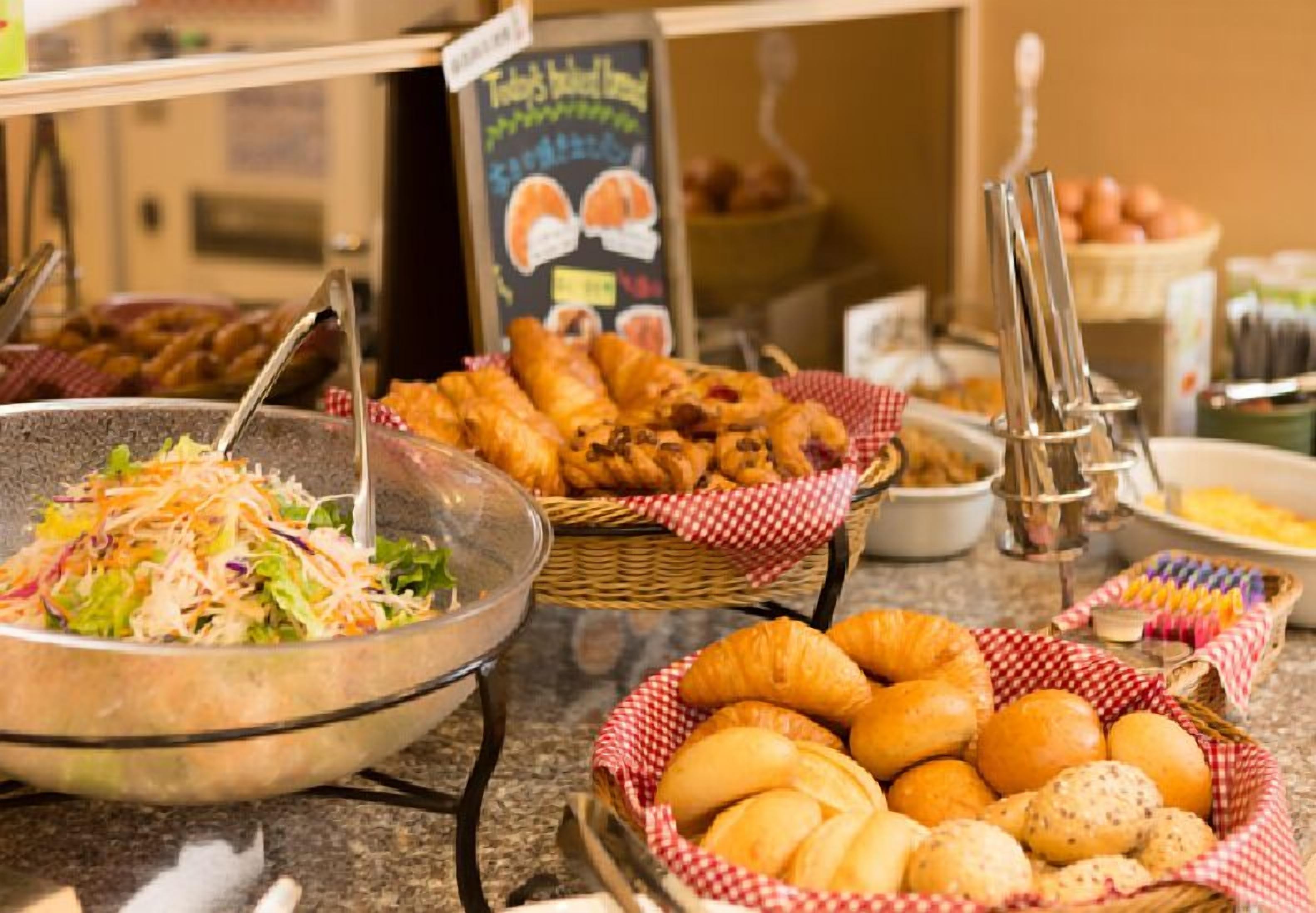 A buffet with various food items including salads, pastries, and bread.