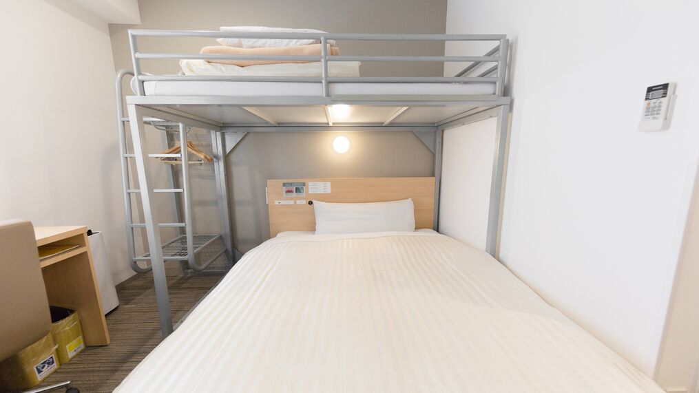 A bunk bed room with a desk and a storage cabinet.