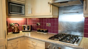 A kitchen with a microwave, toaster, kettle, and gas stove. - The Pinnacle by Jim Paul Apartments (Reading)