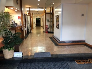 A hotel lobby with a reception desk, potted plants, a staircase, and a clean, polished floor. - Yumura Onsen Totoya (Shinonsen)