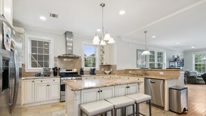 A spacious kitchen with white cabinetry, a large island with bar stools, stainless steel appliances, and pendant lighting. - Luxury Home a Short Walk to Beach and Town with Amazing Reviews  (Point Pleasant Beach)