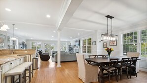 A spacious kitchen with a large island, wooden flooring, and a dining area with a table and chairs. - Luxury Home a Short Walk to Beach and Town with Amazing Reviews  (Point Pleasant Beach)
