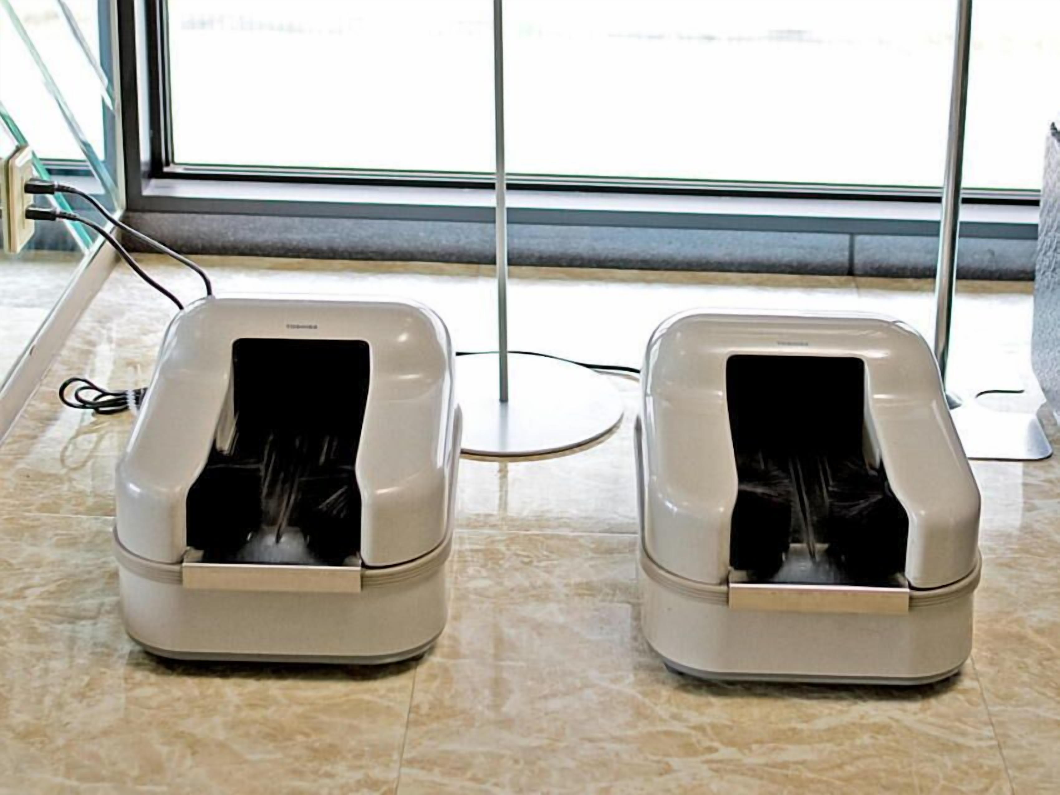 Two pet washing stations in a hotel lobby with a glass partition and a tiled floor.