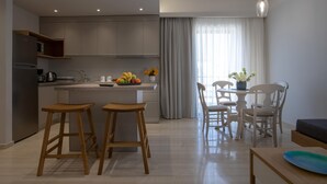 A modern kitchen with a central island, wooden stools, a dining table with chairs, and a pendant light. - Poli Apartment (Chania)