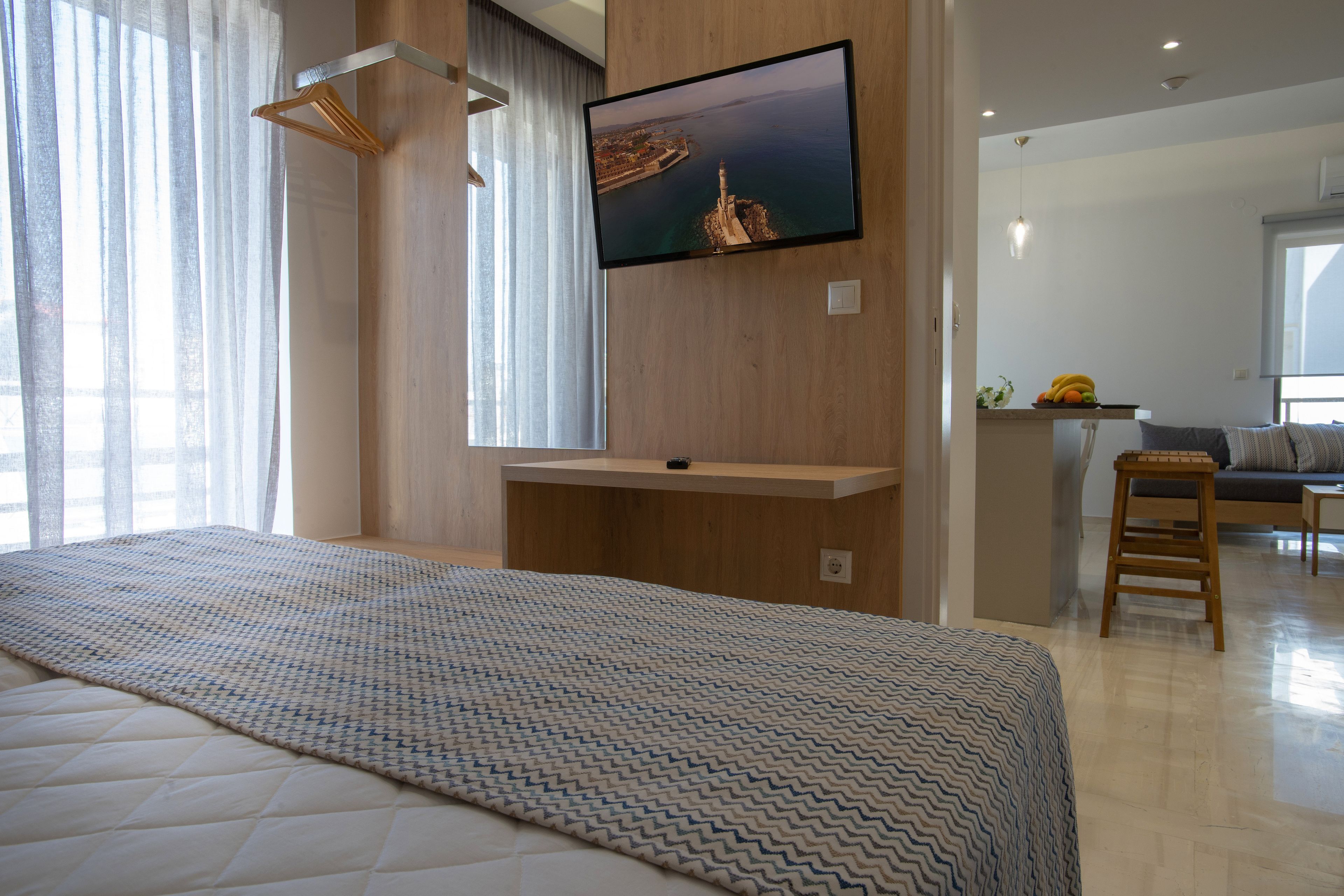 Ein modernes Hotelzimmer mit einem großen Bett, einem Wand-Fernseher und Blick auf eine Küstenlandschaft.