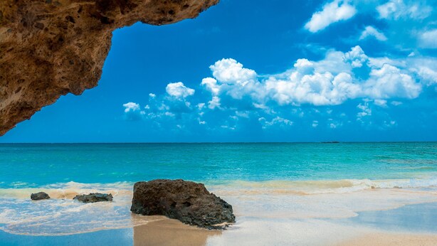 A beach with clear turquoise water, a sandy shore, and a large rock formation in the foreground. - Poli Apartment (Chania)