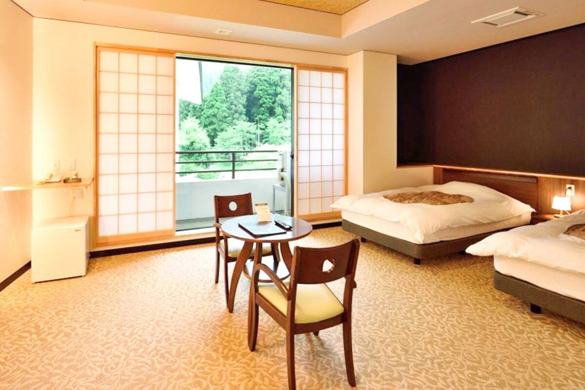Habitación de hotel con puerta corredera a un balcón, cama, escritorio y silla.