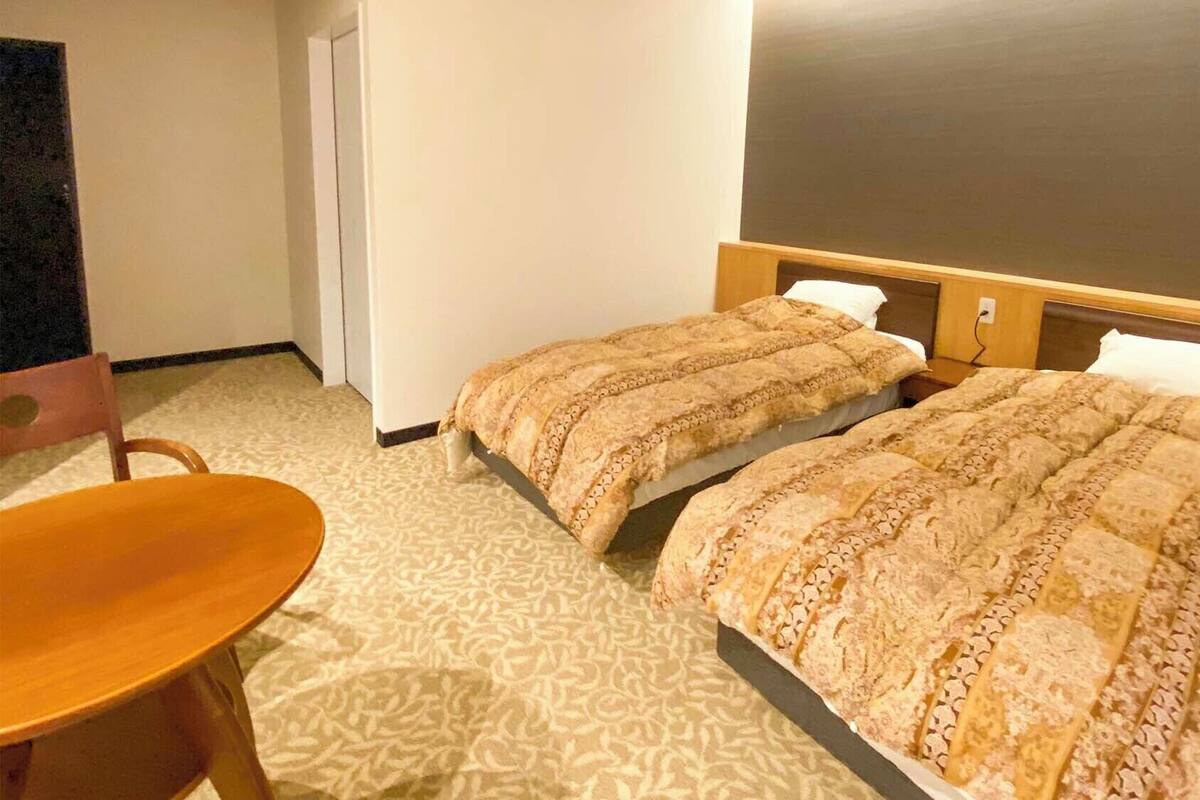 Habitación de hotel con dos camas, una silla de madera y un espejo grande.