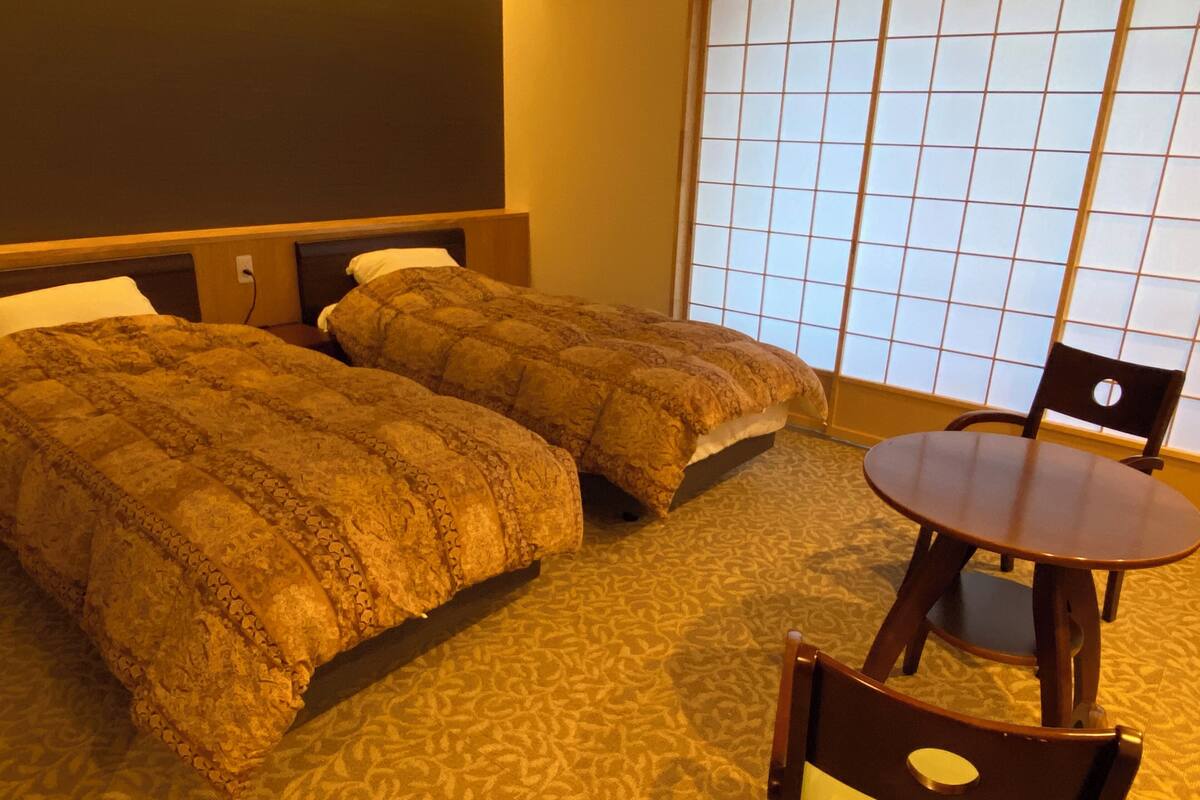 Habitación de hotel con dos camas, una mesa redonda y una silla.