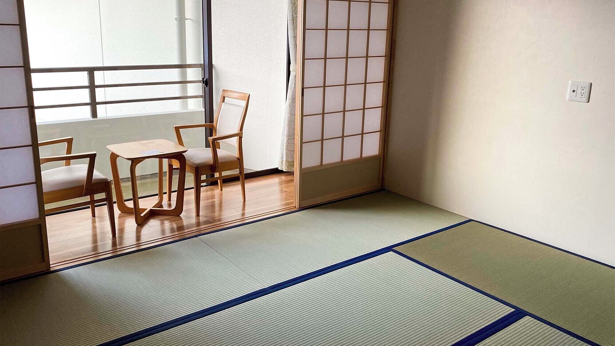 A traditional Japanese room with tatami flooring, a sliding shoji screen, and a low table with chairs.
