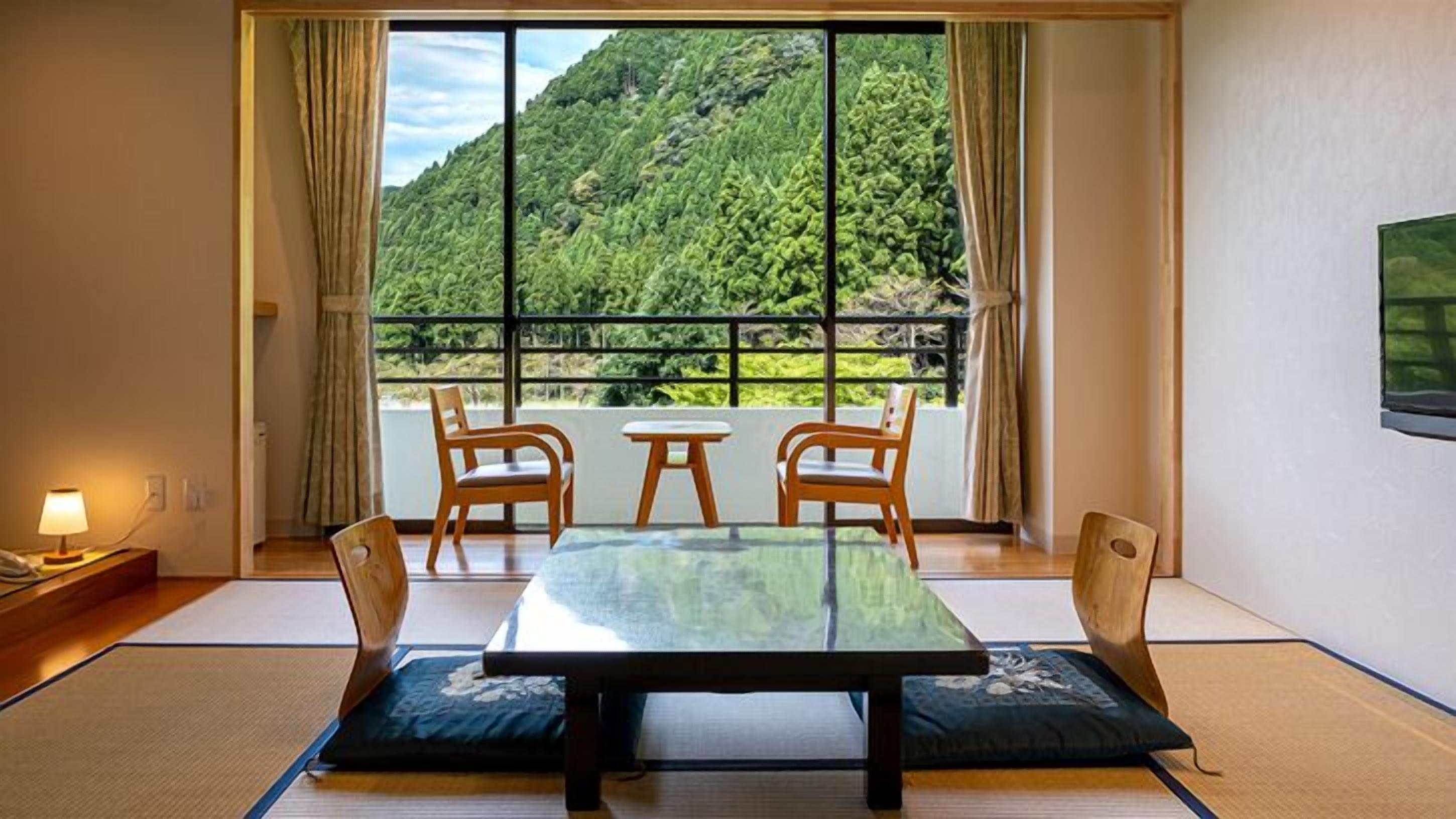 A traditional Japanese room with tatami flooring, a low table, and four wooden chairs.