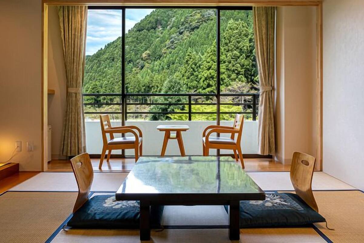 Una habitación japonesa tradicional con suelo de tatami, una mesa baja y cuatro sillas de madera.