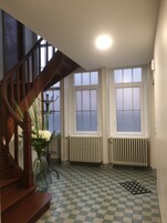 A staircase with wooden railings, a checkered floor, and a radiator near a window.