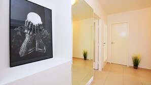 Ein Flur mit einem gerahmten Kunstwerk, das eine Roboterhand zeigt, einer weißen Tür und zwei Topfpflanzen.