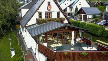 A two-story building with a balcony area featuring outdoor seating and a view of the surrounding neighborhood.