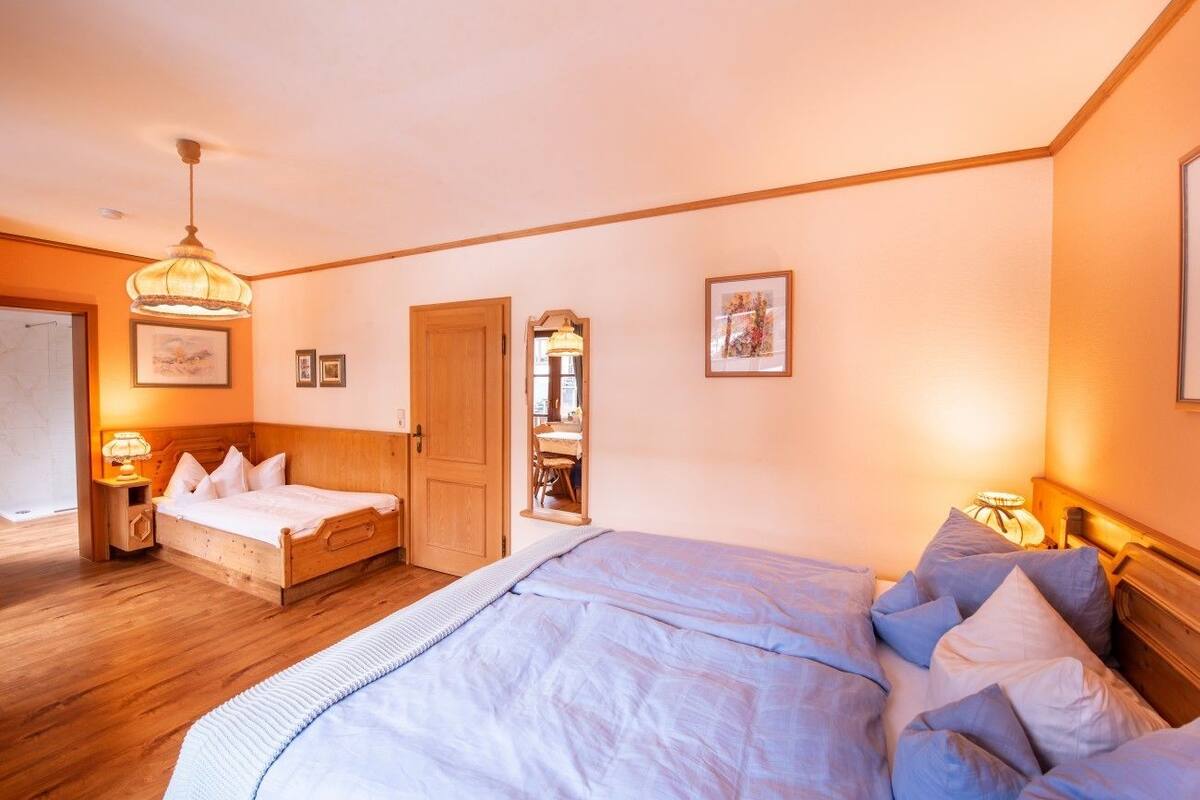 Ein Schlafzimmer mit einem großen Bett, einem Holzschrank, einem Schreibtisch mit Stuhl und einer Pendelleuchte.